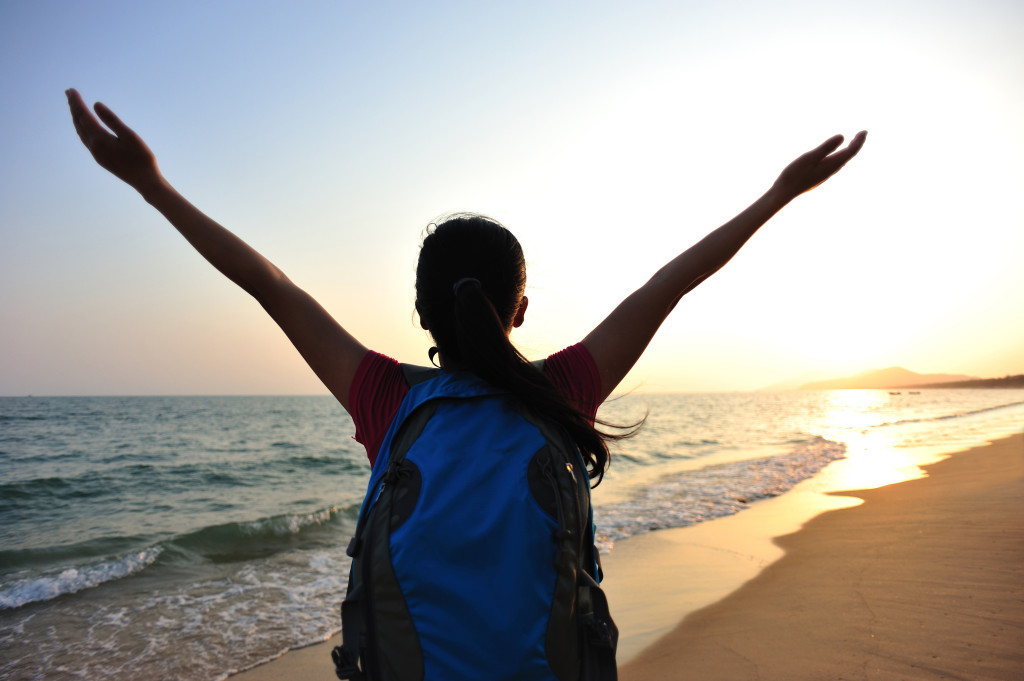 cheering woman hiker open arms at sunrise seaside beach open be